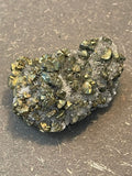 Funkelnder Mineralstein mit goldenen, weißen und dunklen Kristallen.