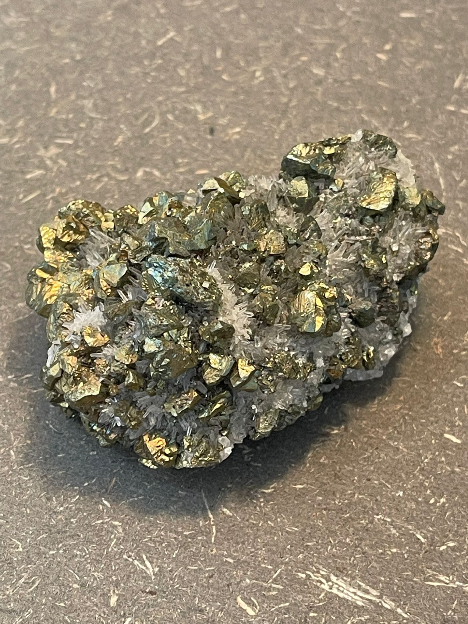 Funkelnder Mineralstein mit goldenen, weißen und dunklen Kristallen.