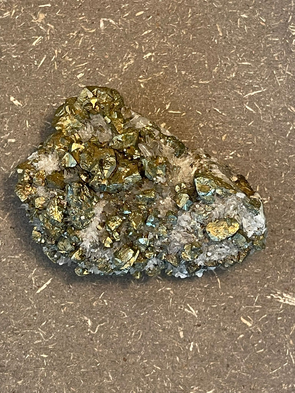 Funkelnder Mineralstein mit goldenen, weißen und dunklen Kristallen.