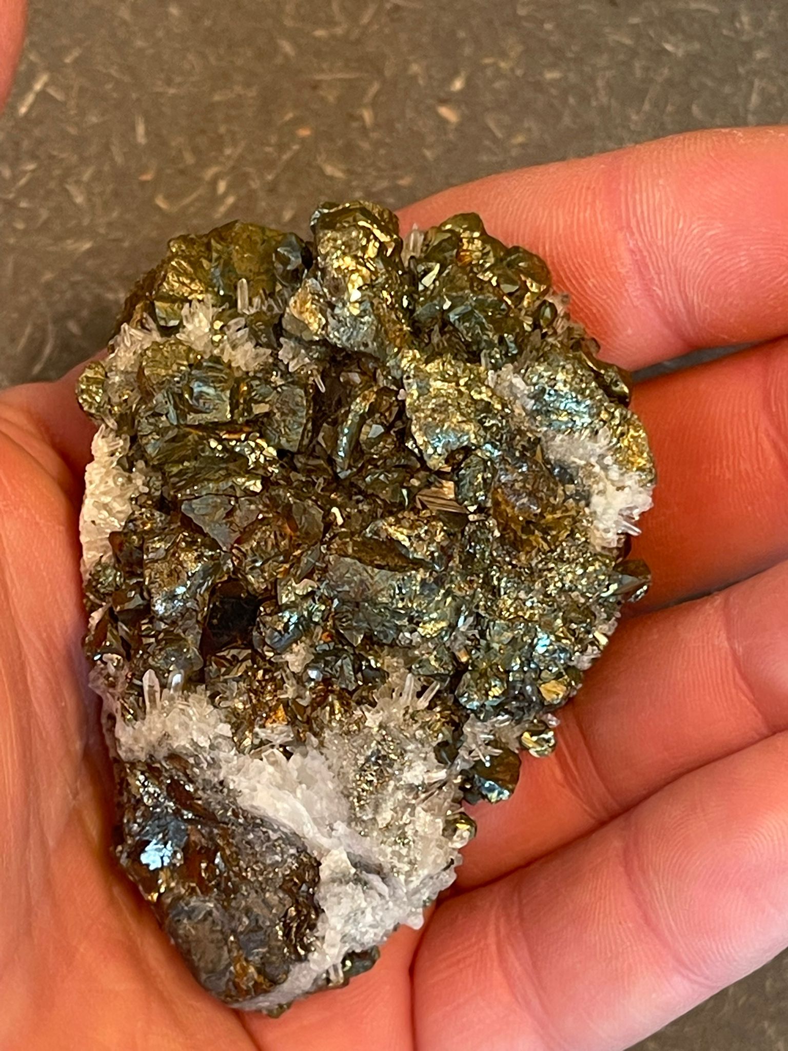 Funkelnder Mineralstein mit goldenen, weißen und dunklen Kristallen.