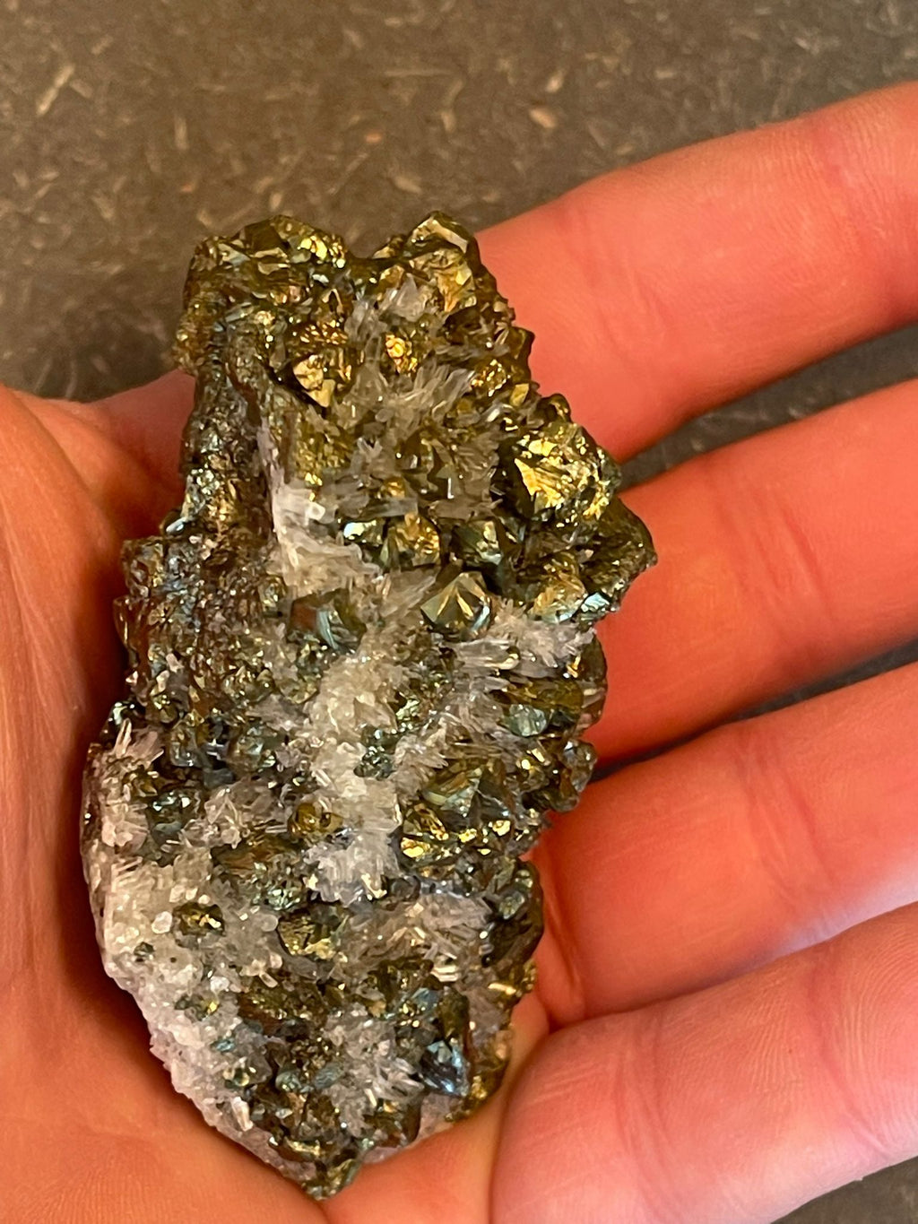 Funkelnder Mineralstein mit goldenen, weißen und dunklen Kristallen.