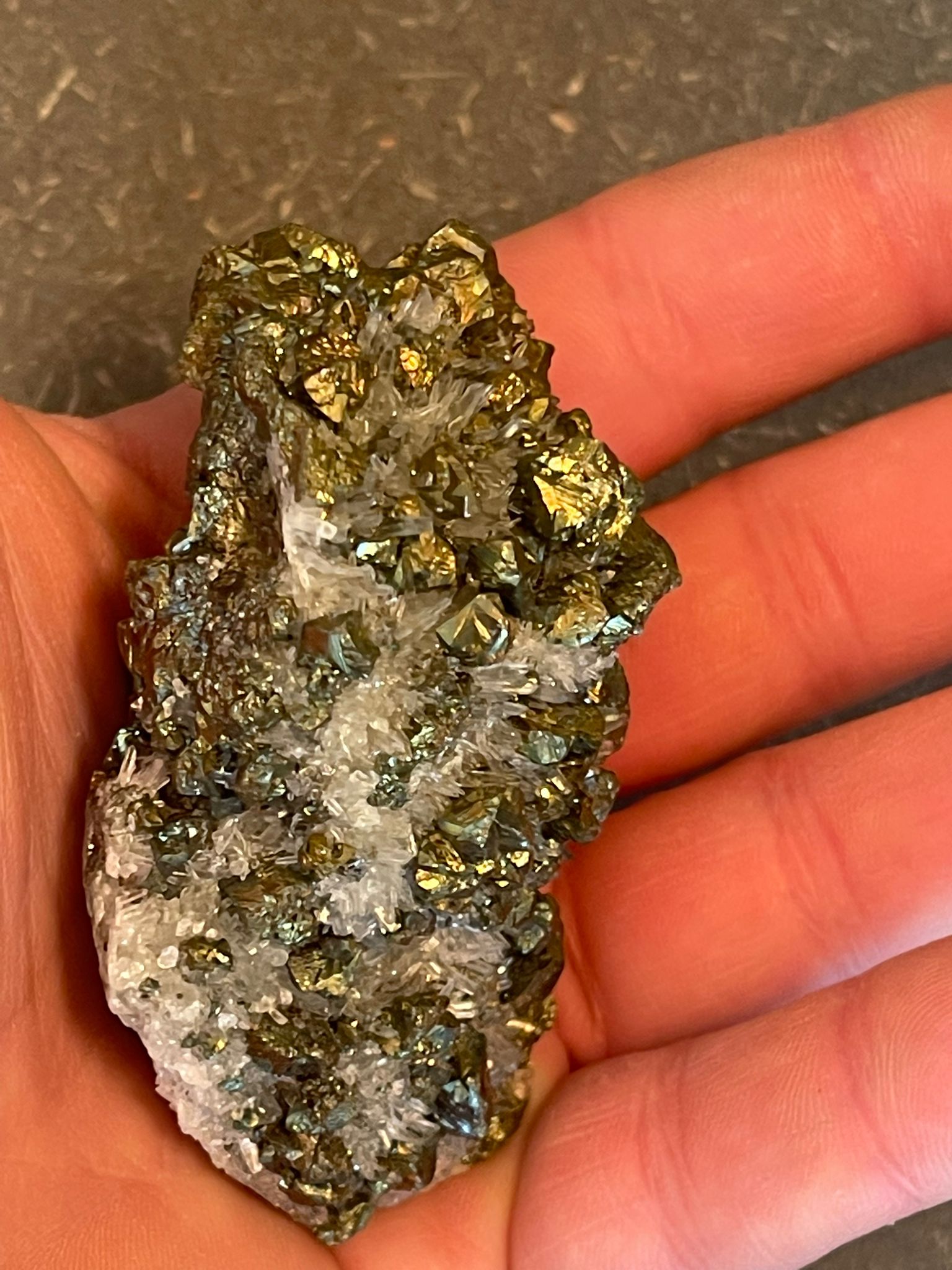 Funkelnder Mineralstein mit goldenen, weißen und dunklen Kristallen.