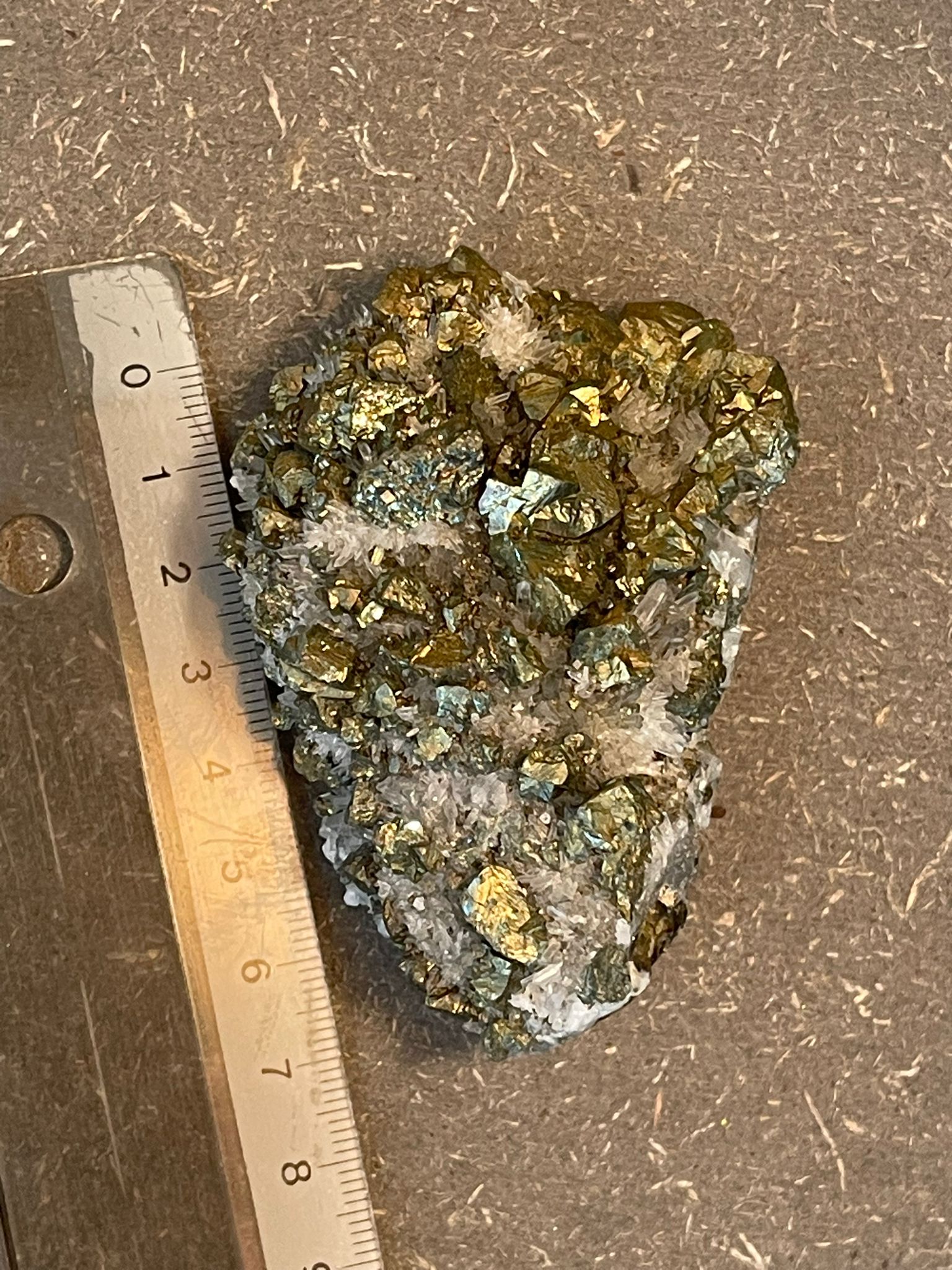 Funkelnder Mineralstein mit goldenen, weißen und dunklen Kristallen.