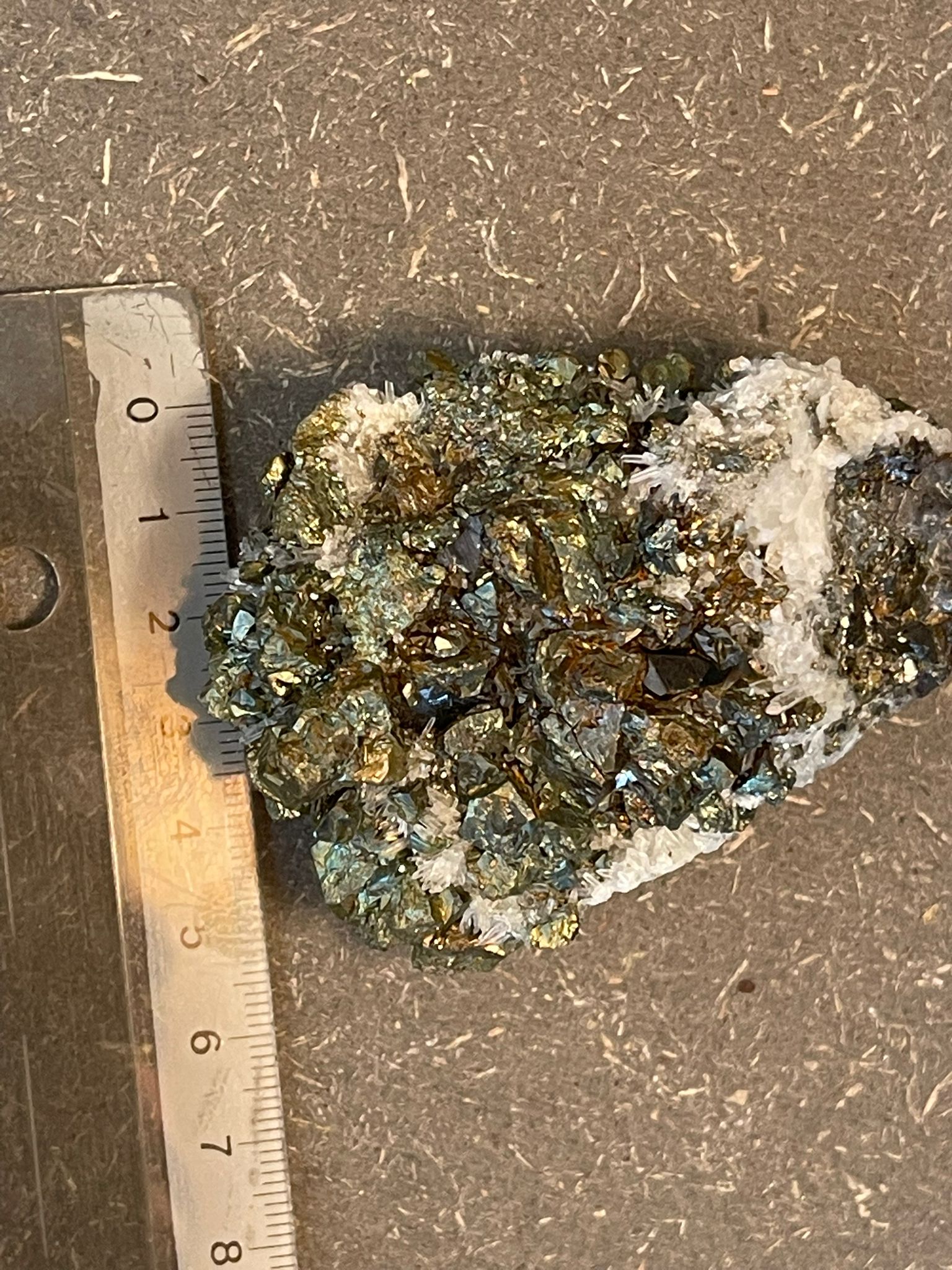 Funkelnder Mineralstein mit goldenen, weißen und dunklen Kristallen.