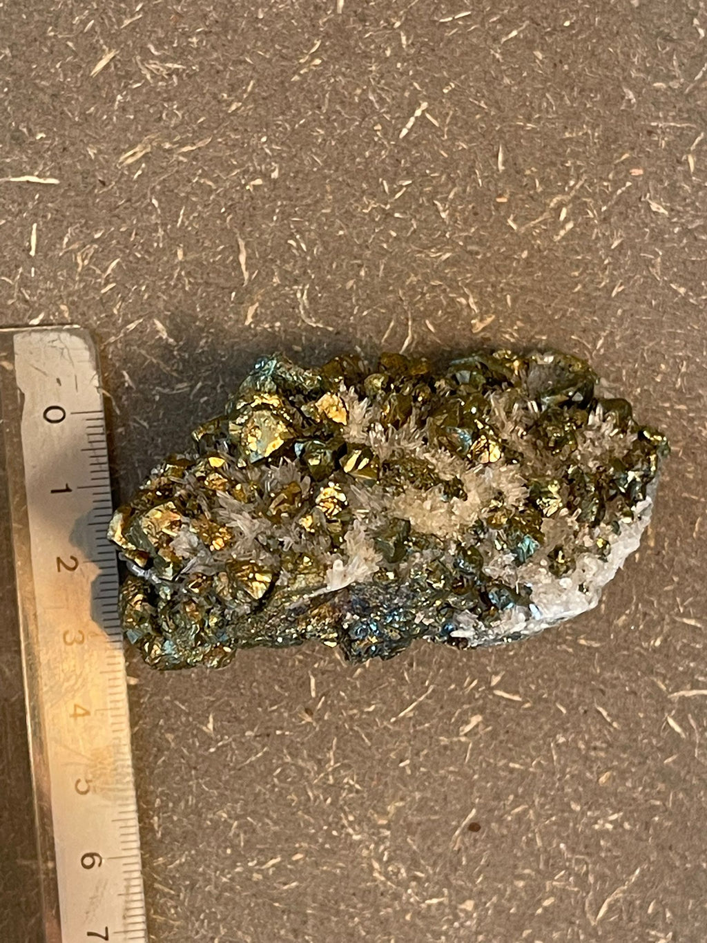 Funkelnder Mineralstein mit goldenen, weißen und dunklen Kristallen.