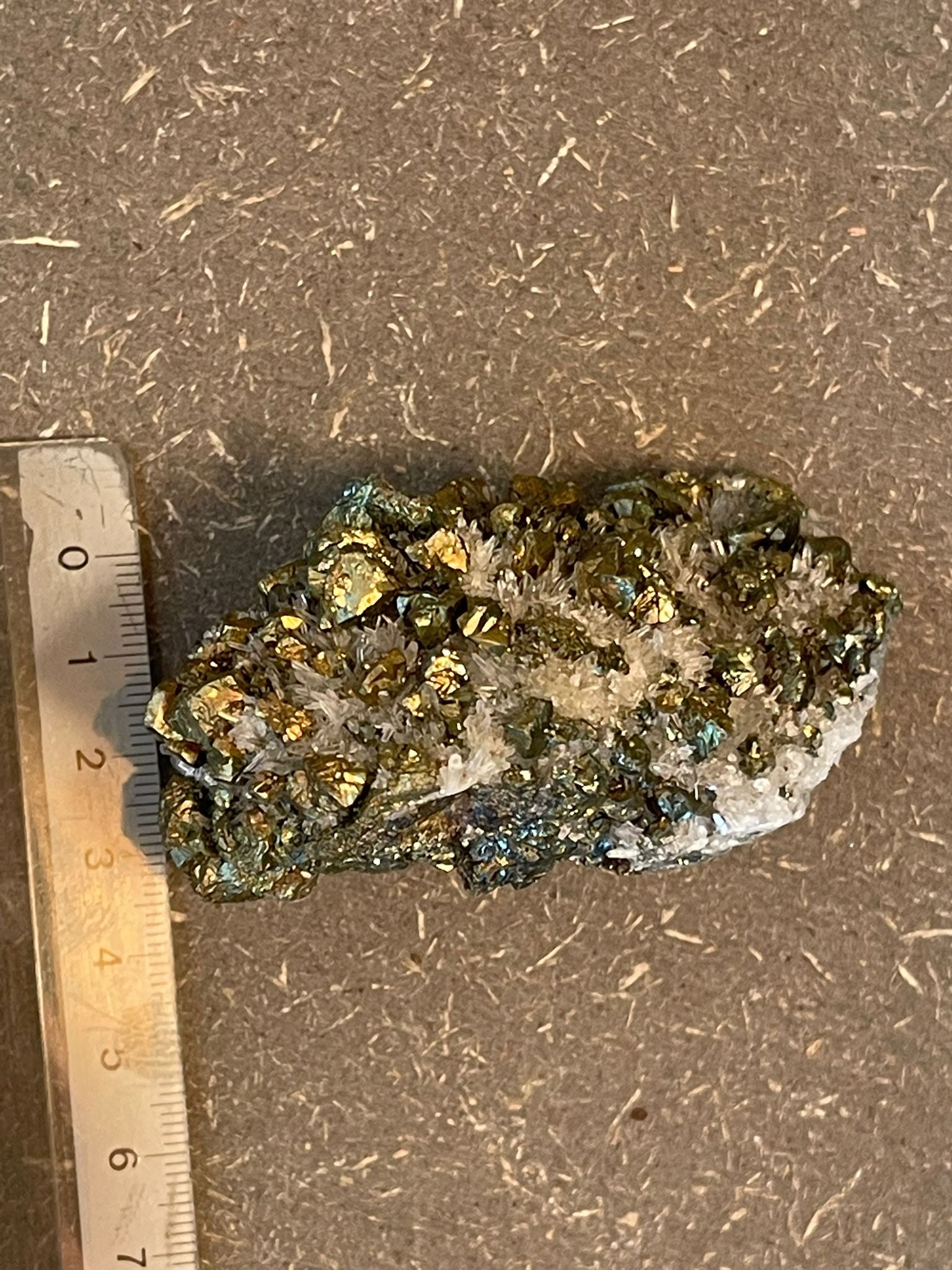 Funkelnder Mineralstein mit goldenen, weißen und dunklen Kristallen.