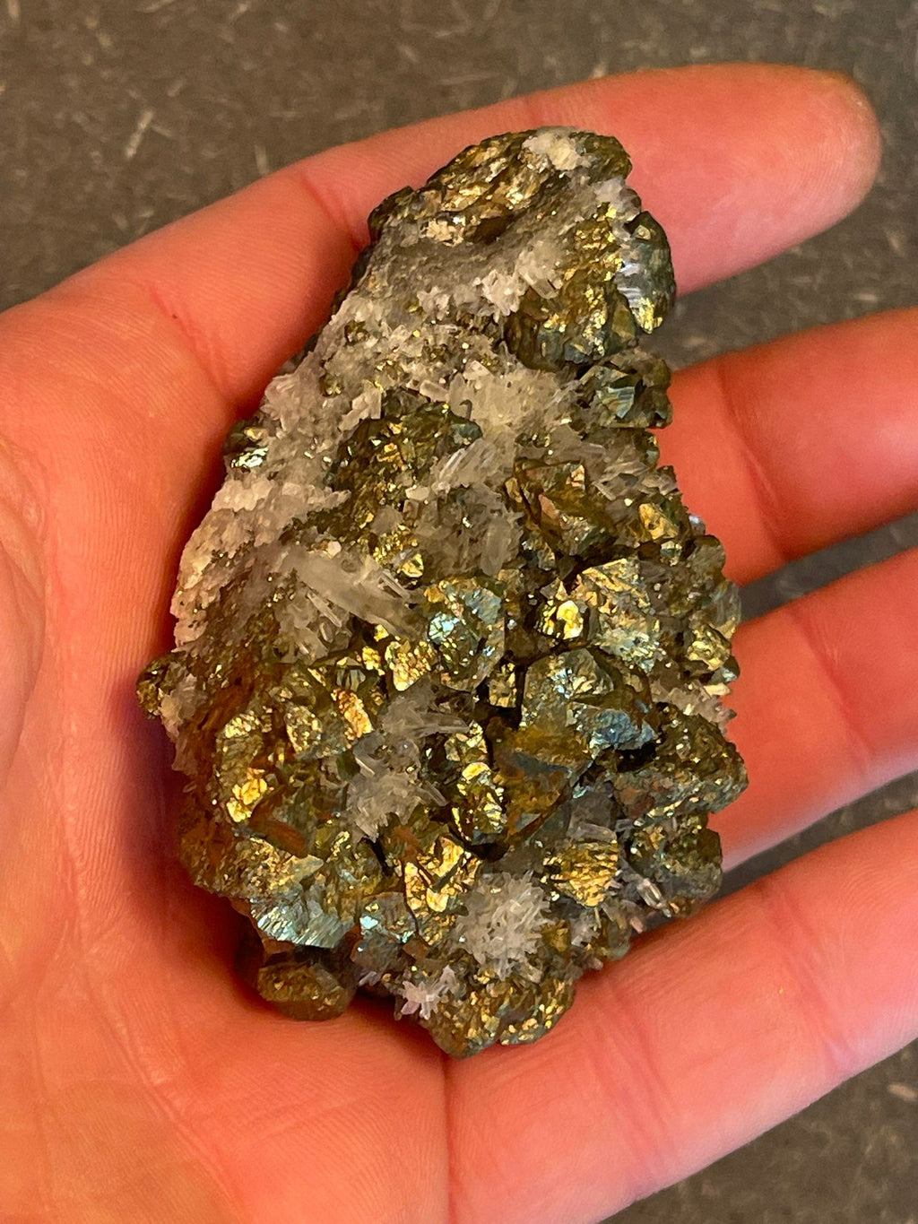 Funkelnder Mineralstein mit goldenen, weißen und dunklen Kristallen.