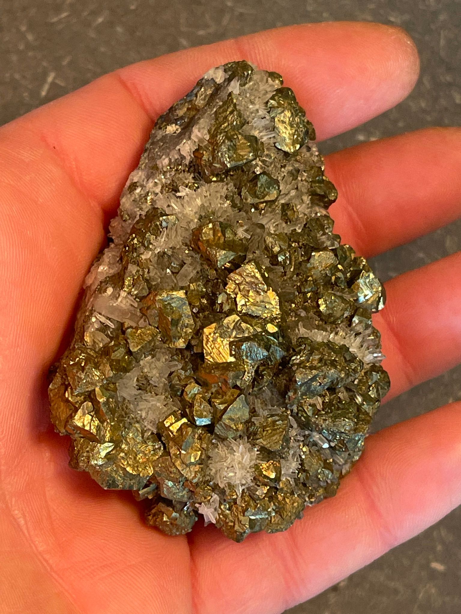 Funkelnder Mineralstein mit goldenen, weißen und dunklen Kristallen.