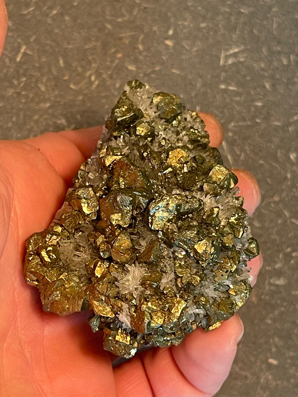 Funkelnder Mineralstein mit goldenen, weißen und dunklen Kristallen.