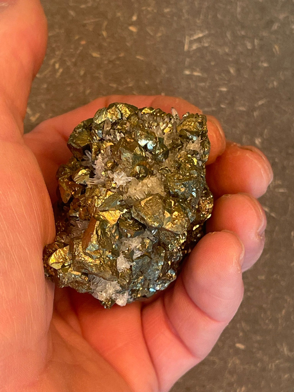 Funkelnder Mineralstein mit goldenen, weißen und dunklen Kristallen.