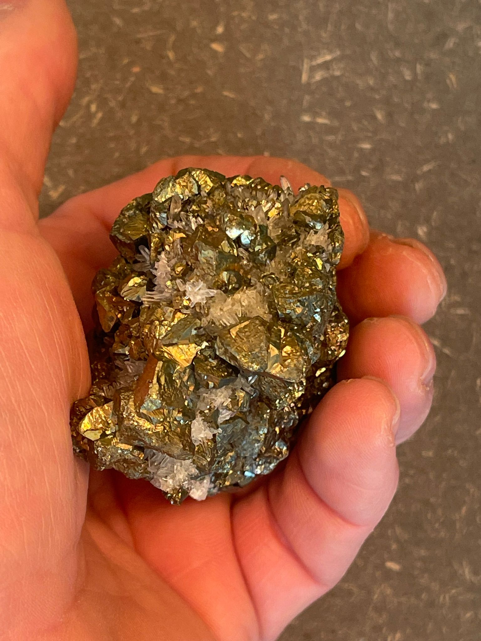 Funkelnder Mineralstein mit goldenen, weißen und dunklen Kristallen.