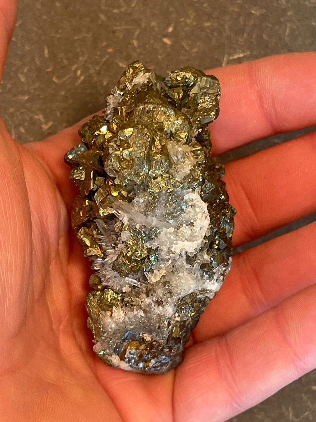 Funkelnder Mineralstein mit goldenen, weißen und dunklen Kristallen.